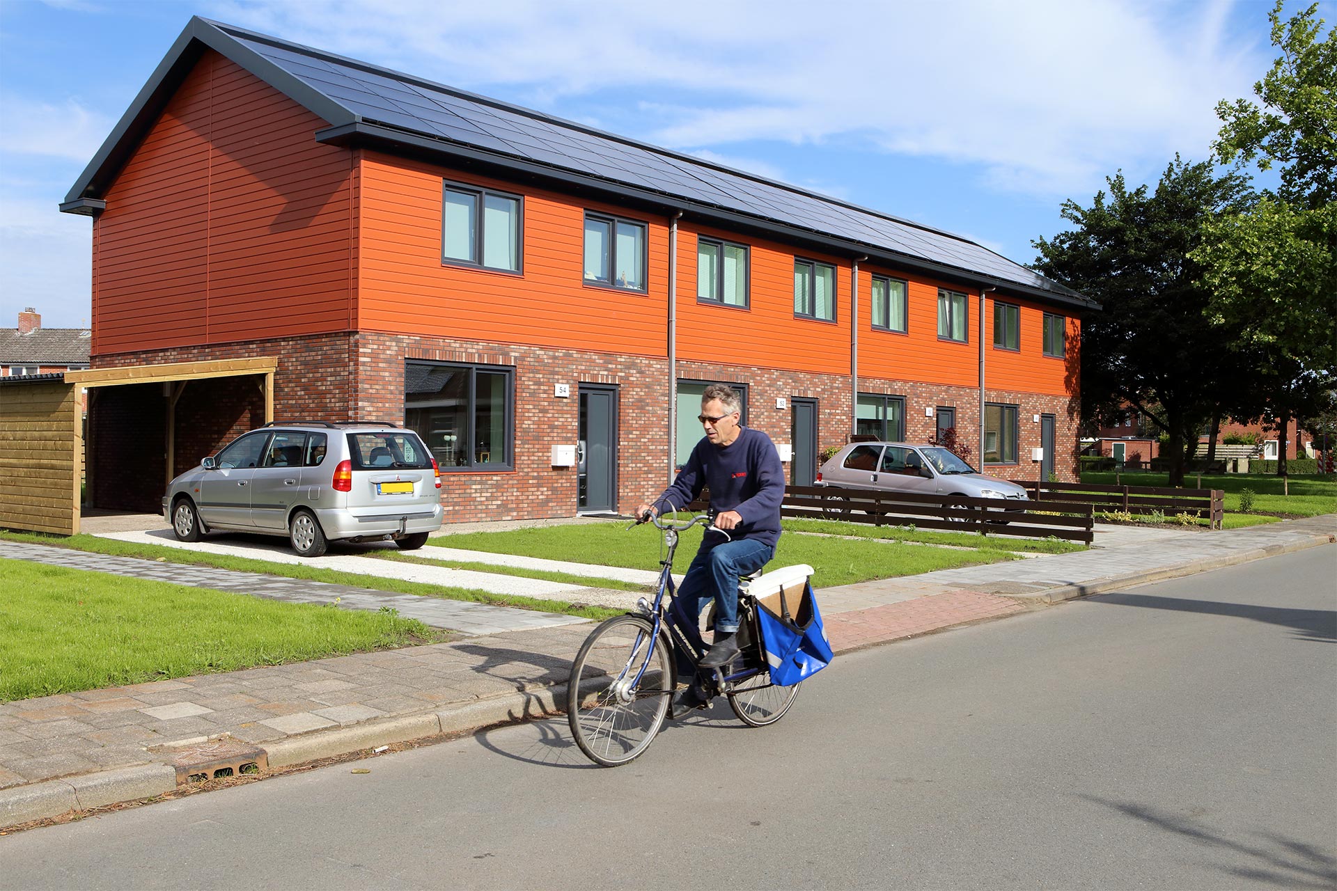 Man op de fiets voor rijtjeswoningen met zonnepanelen